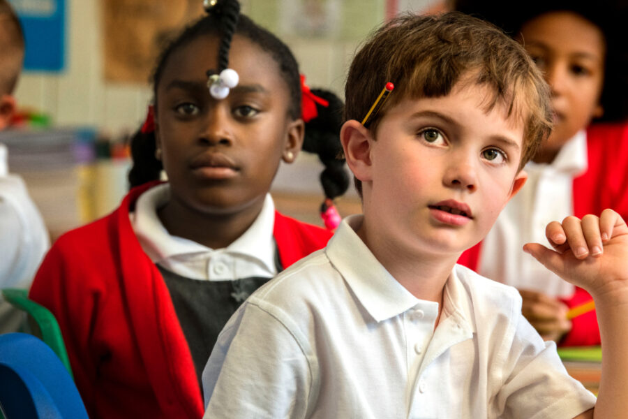 A close up photo of two young children concentrating on the teacher talking through some instructions.