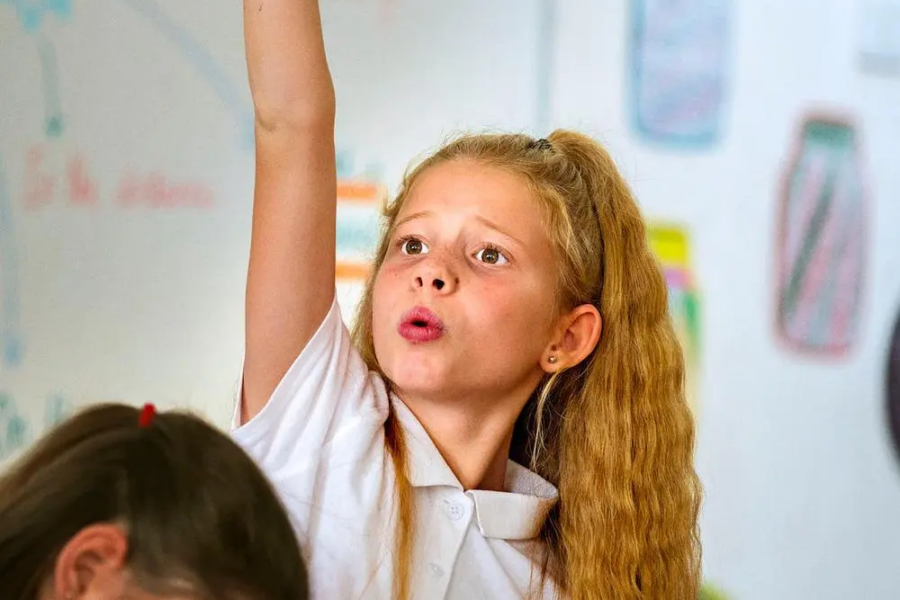 Child raising her hand in a classroom